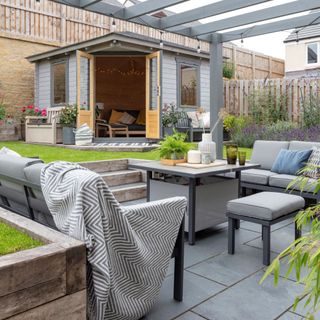 Outdoor seating area on patio decorated with plants and throws