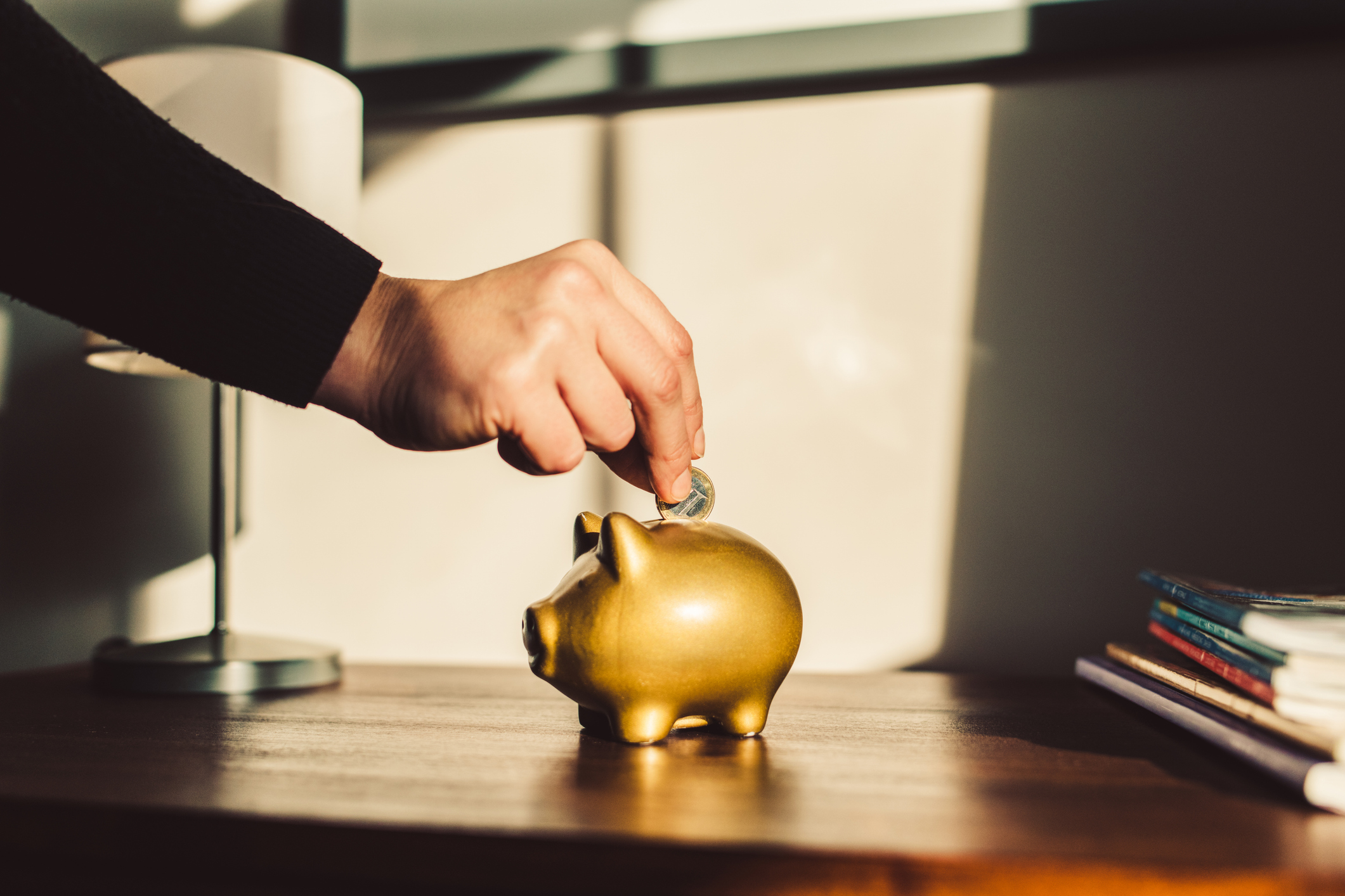 Woman putting coin into a golden piggy bank.