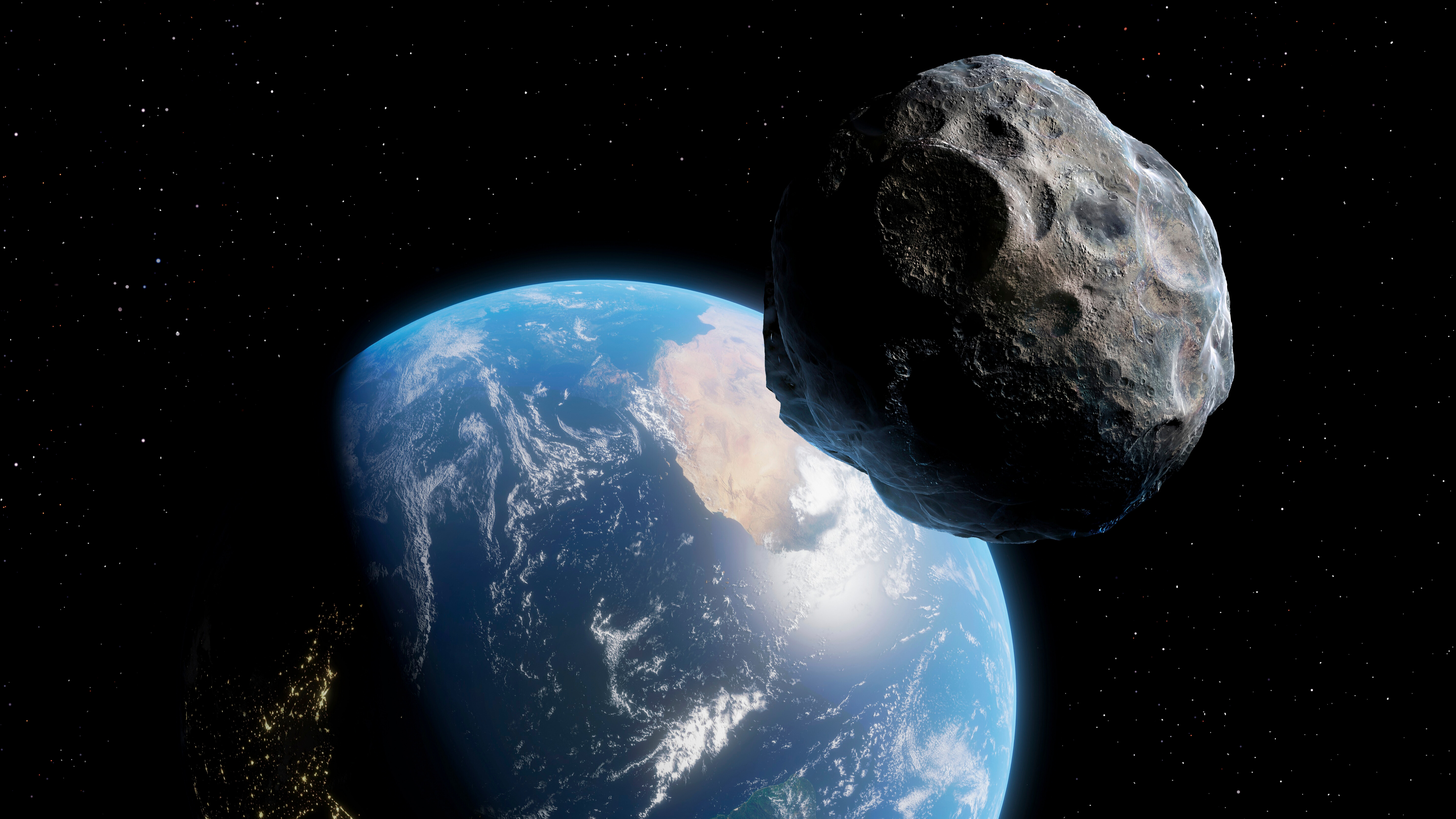 a lumpy grey rock covered in craters floats in front of a blue-and-white earth beneath it. hundreds of pinpoint-like stars dot the black background of space