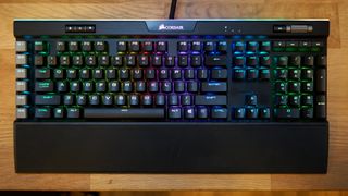 Et Corsair K95 RGB Platinum-tastatur ligger på et trefarget skrivebord.