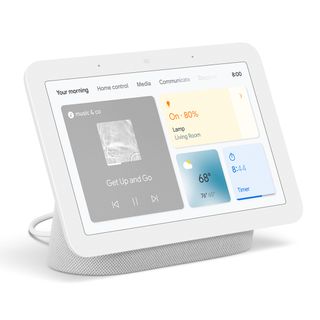 A white Google Nest Hub (2nd Generation) on a white background. It is almost all screen with a white bezel surrounding it and grey base. The screen has four panels on it showing music, weather, a timer, and controls for a lamp.