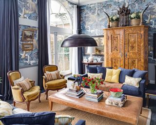 A small living room with blue patterned wallpaper and antique furniture