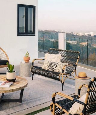 An outdoor balcony area with garden furniture and assortment of outdoor cushions