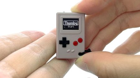 Hand holding TinyCircuits Thumby console between fingers