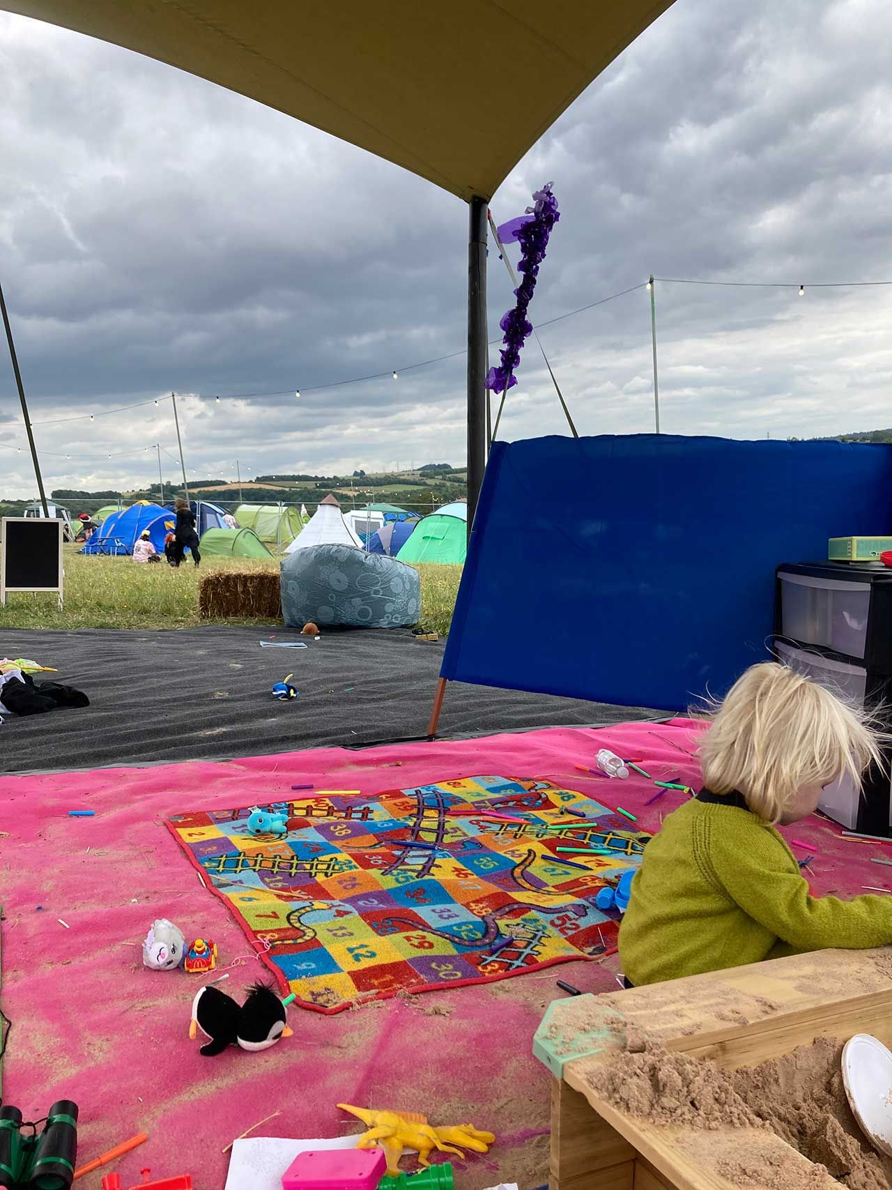 A young boy plays in a sandpit/play area in a festival camping area