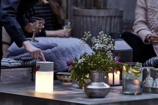 table at dusk with an LED outdoor speaker and other candles