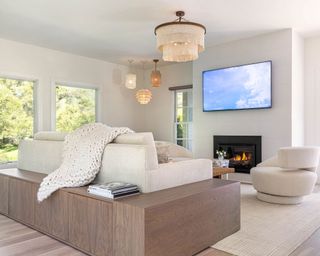 bright living room in a white and natural color palette, four textured pendant lights, large cream sofa and dark wood sofa, cream rug and lounge chair