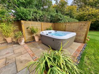 hot tub from HydroLife on paving with fence