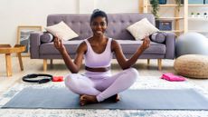 woman sits cross-legged on yoga mat