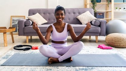 woman sits cross-legged on yoga mat