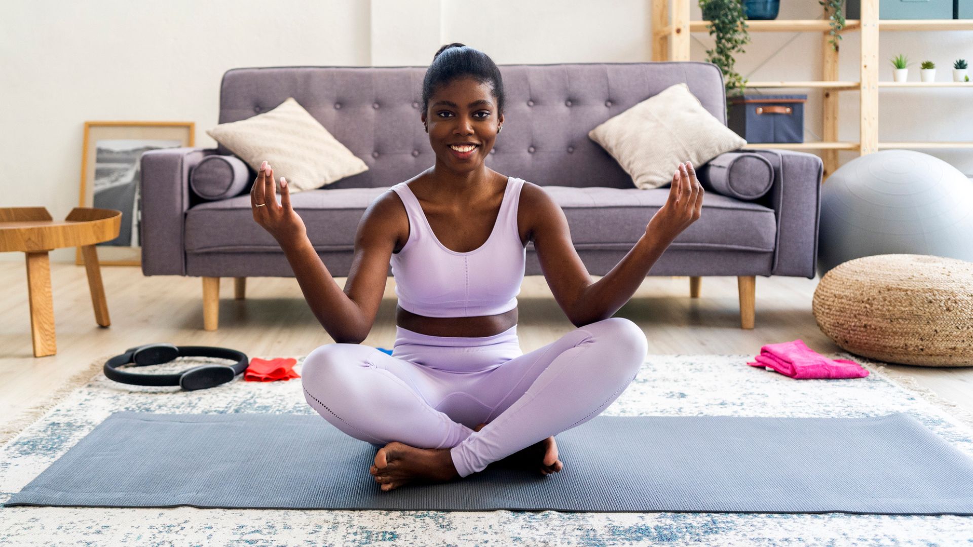 woman sits cross-legged on yoga mat