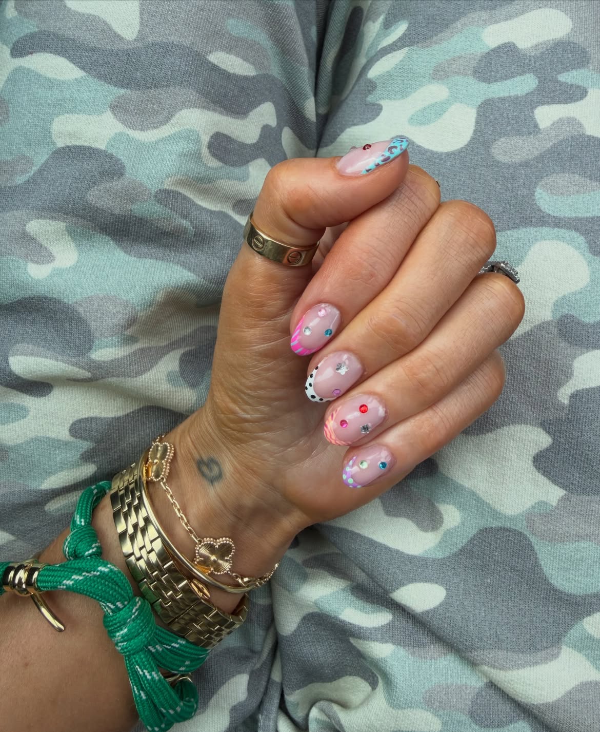 sheer pink nails french manicure with black and white, pink, and orange animal print and tiny gems