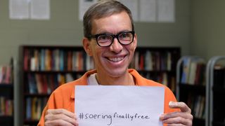  Jens Soering wearing orange prison clothes holds up a sighttps://cdn.mos.cms.futurecdn.net/YMjexkmSYSXrnvnpiva9UQ-600-80.jpgn that he plans to use for his social media after he's deported back to Germany