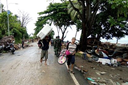 Residents evacuate from damaged homes on Carita beach on December 23, 2018, after the area was hit by a tsunami on December 22 that may have been caused by the Anak Krakatoa volcano.