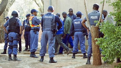 Police stand guard as miners allegedly involved in violent clashes between protesting workers and police at the Marikana mine arrive at the Ga-Rankuwa courthouse, 37kms from Pretoria, on Augu
