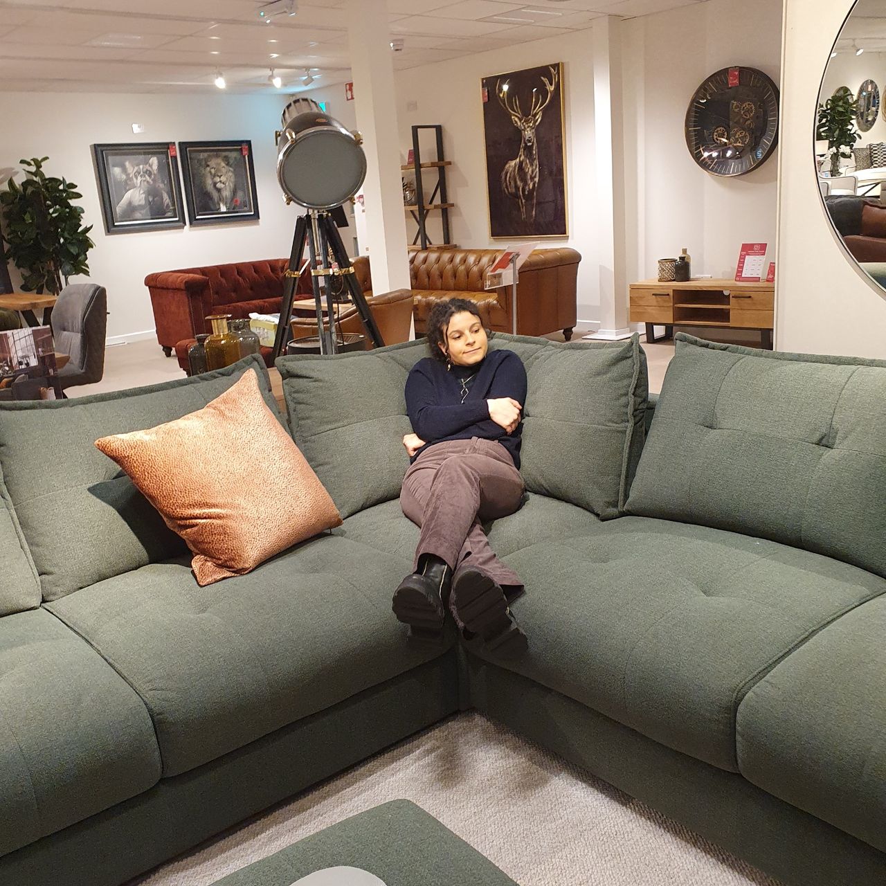 Sara sitting on the Furniture Village Boutique Goliath sofa in dark moss green