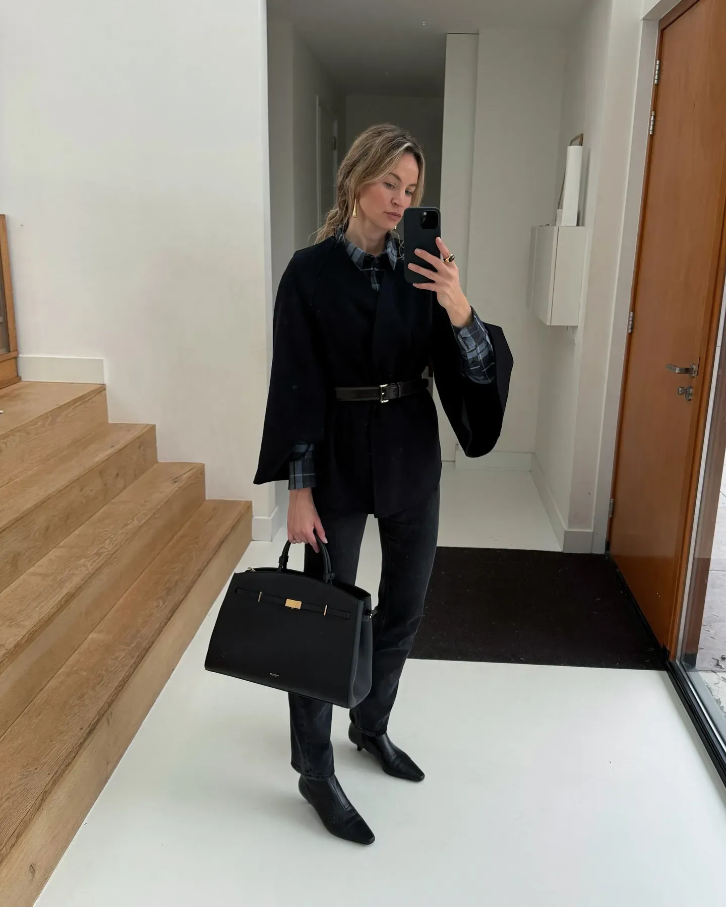 Anouk wearing a black DeMellier Bag, black jeans, black boots and a black jacket.