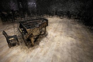 Chiharu Shiota's installation, In Silence at the Mori Art Museum in Tokyo, comprising a black Alcantara thread emanating from a burnt piano and chair