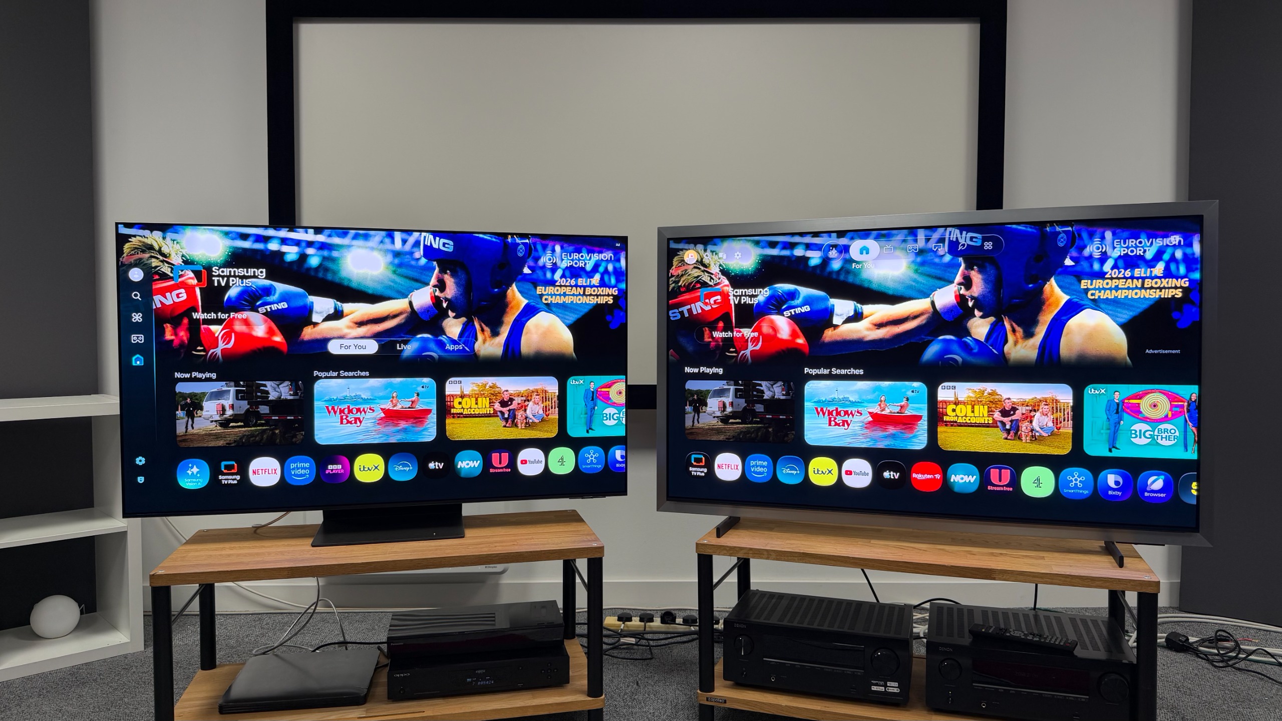 The 55-inch Samsung S99H and S95H OLED TVs, picture side by side on wooden racks