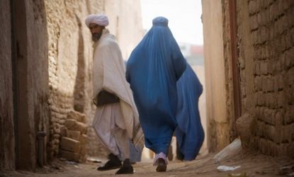 A man looks back as women walk along an alley in Herat, Afghanistan.