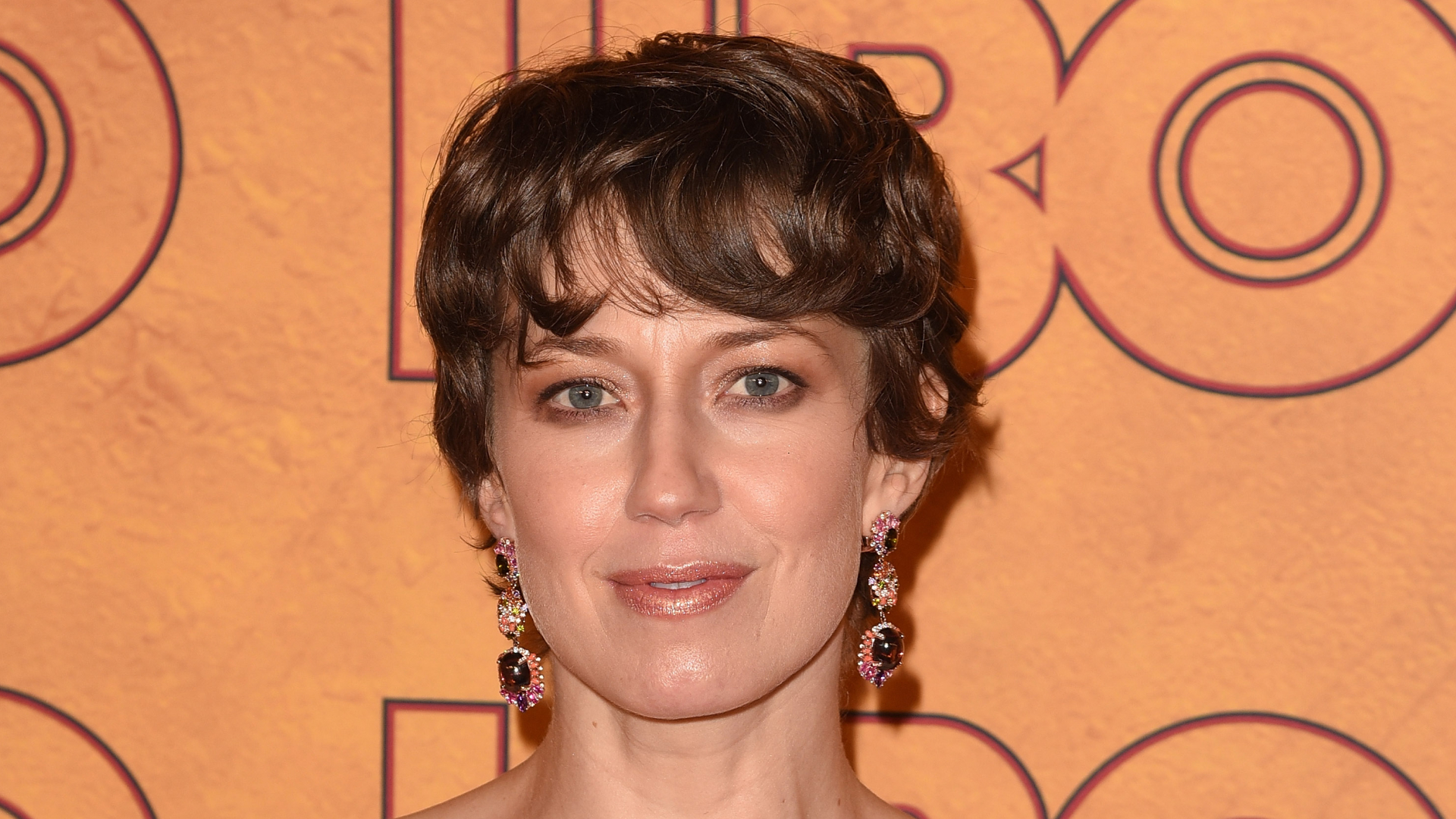 Carrie Coon with a pixie haircut and dangly earrings.