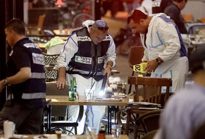 Israeli forensic police inspect a restaurant following a shooting attack at a shopping complex in the Mediterranean coastal city of Tel Aviv on June 8, 2016.