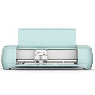 Product shot of one of the best vinyl cutter machines; a mint green digital craft machine with its lid and draw open so you can see its cutting blade
