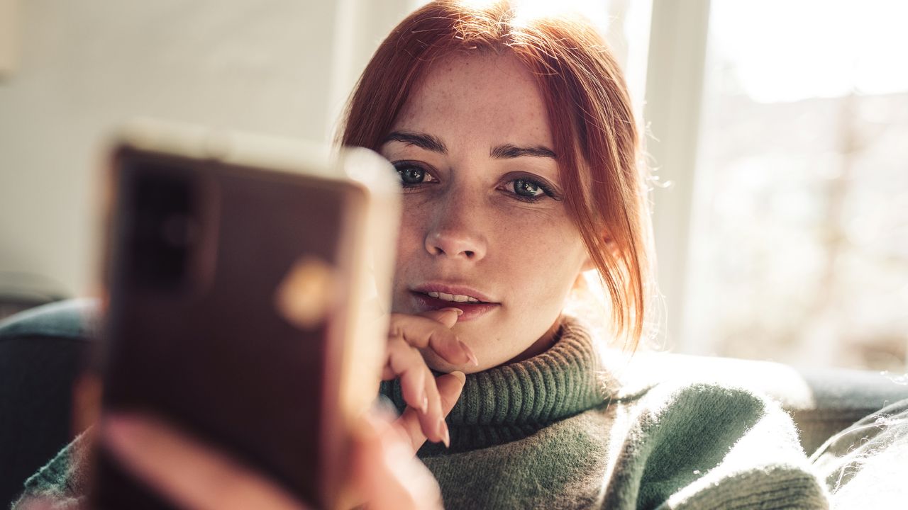 A young woman looks at her phone.