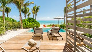 Wooden decking and sunloungers by a pool and ocean view beyond at an Andaz Mayakoba Bilevel Suite