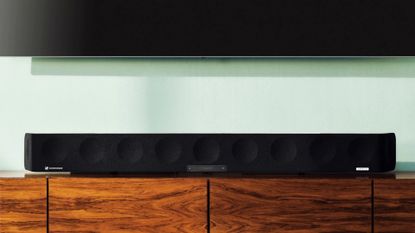 best soundbar: Sennheiser Ambeo placed on wood TV stand against light green wall