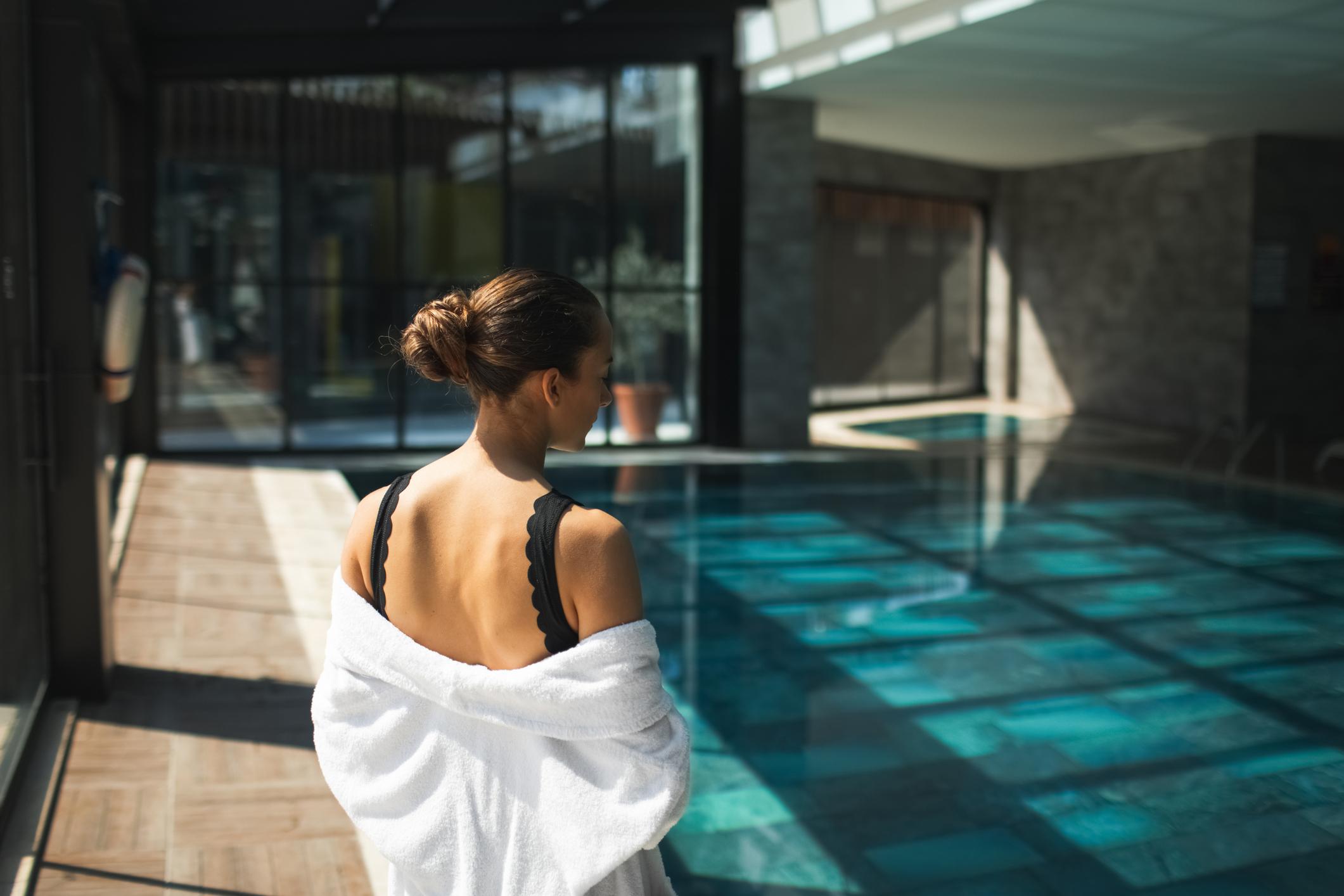  Woman in towel standing in front of blue spa pool 