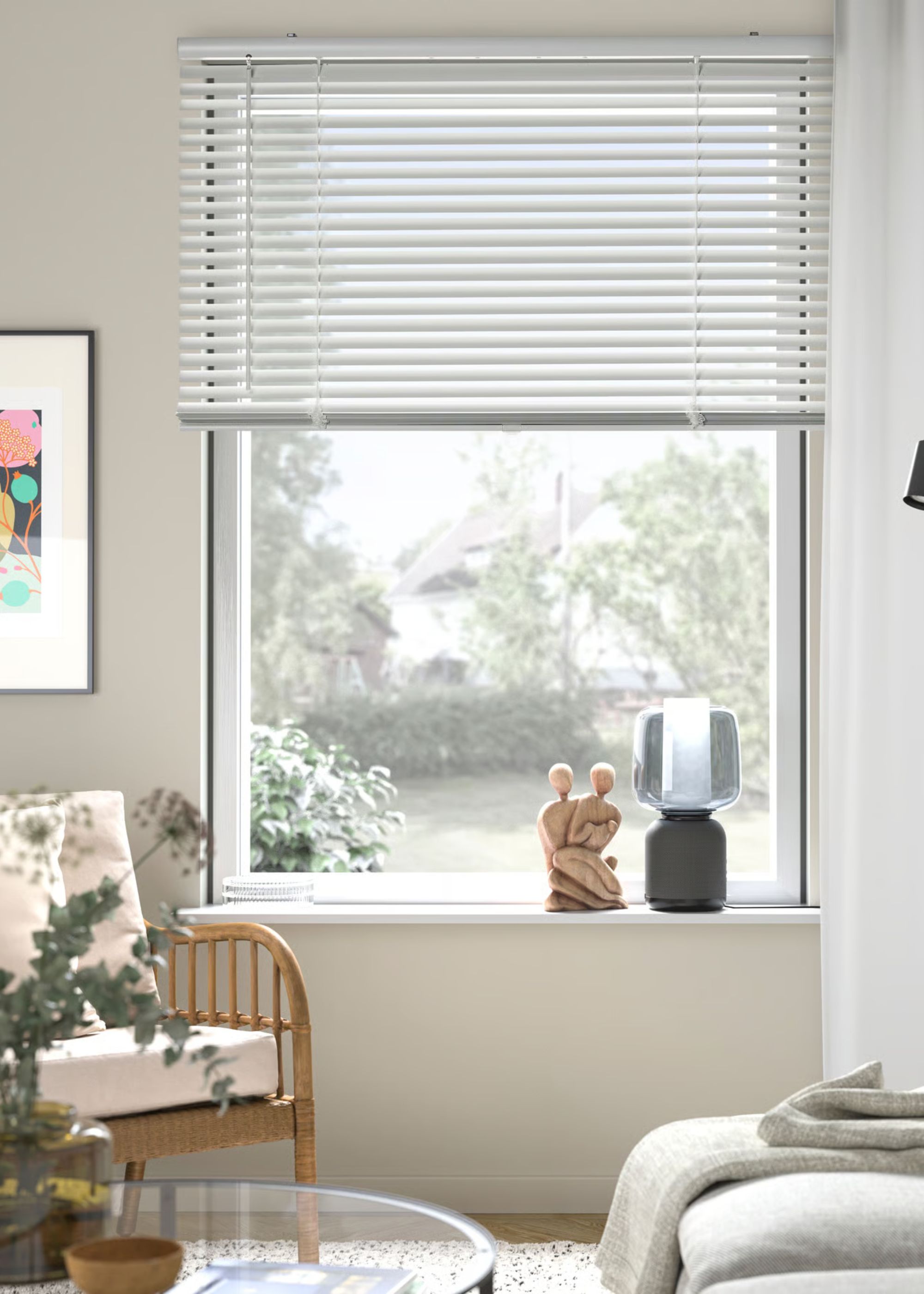 Readymade blinds placed on a window. On the windowsill is a lamp and piece of decor. There is also a chair beside the window facing the other side of the room