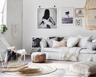 Relaxed mono boho living space with layered, tactile materials, cushions galore, round jute rug, rocking chair with faux fur rug, large natural pendant, and black and white gallery wall idea.