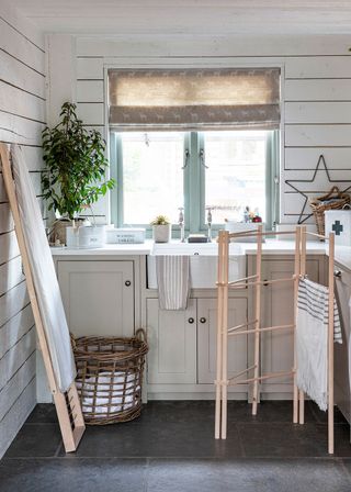 Small laundry room ideas with white shiplap paneling, a butler sink and gray slate floor.