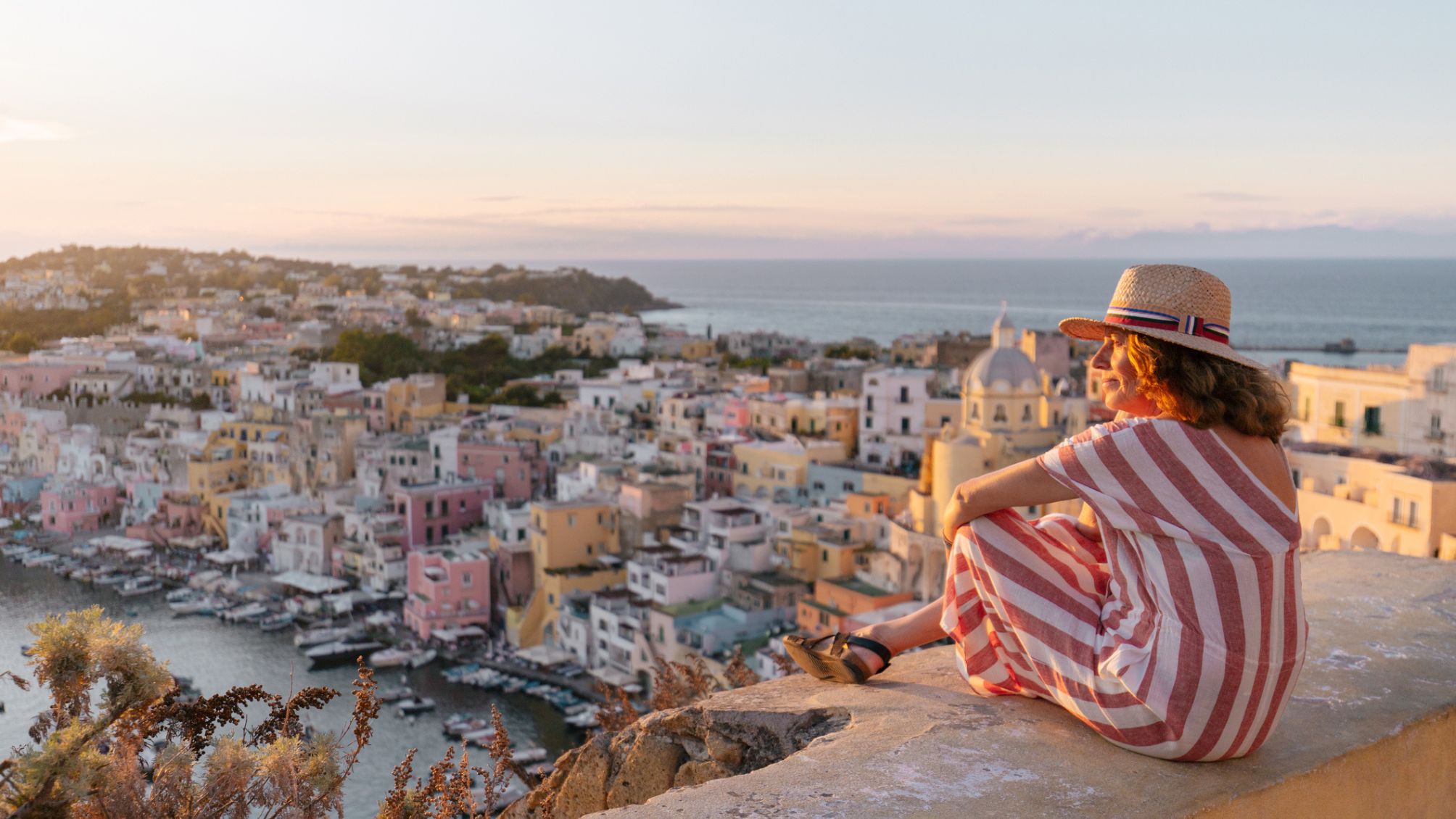 Mature woman admiring Procida sunset cityscape 