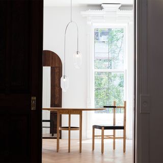 Sliding door looking into a dining room with wooden table and chairs and hanging lighting fixture