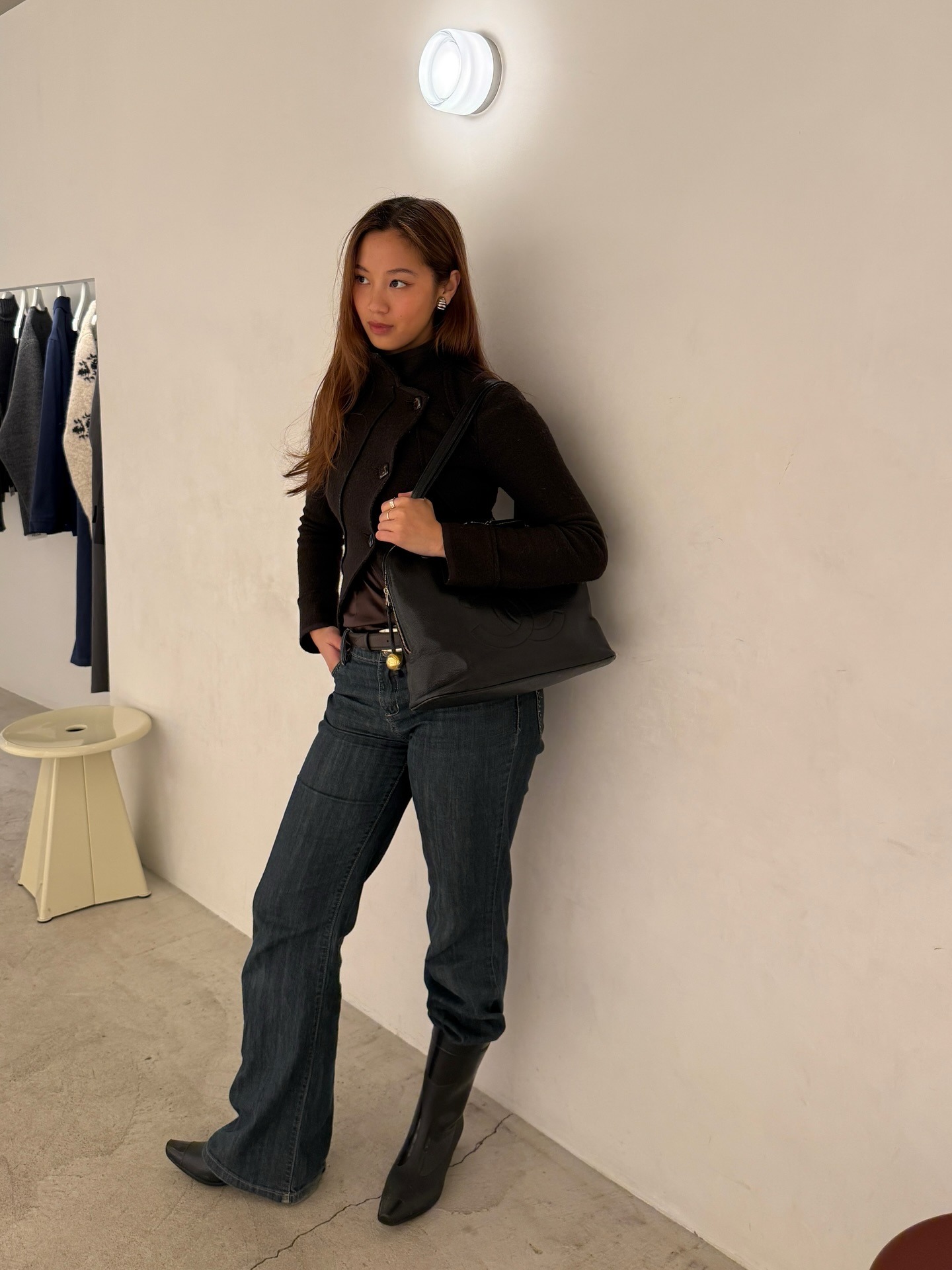 Fashion person Isa Sung wears the tucked knee high boot trend. She wears dark wash boot cut jeans, black boots and a knitted cardigan. This image was recently taken from her Instagram.