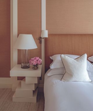 bedroom with orange textured walls and white bedding and sidetable