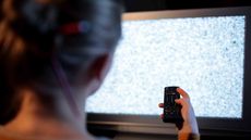Woman with remote watching static on tv 
