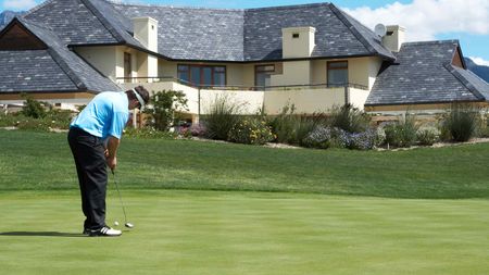 Golfer putting on a golf course with large homes nearby