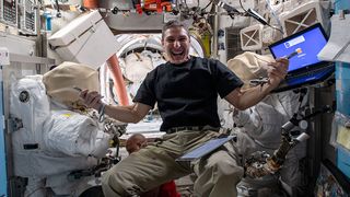 NASA astronaut Mike Hopkins flashes a big smile in a photo posted by the International Space Station on Jan. 21, 2021. The photo shows Hopkins with some other crew members and a pair of spacesuits in the background, surrounded by equipment, working on science experiments and training for an upcoming pair of spacewalks.