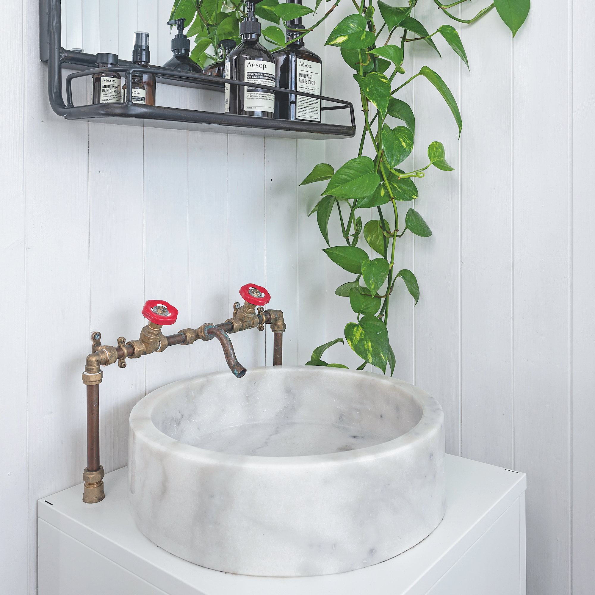 bathroom marble basin with brass exposed pipe taps with red knobs