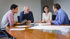 A multigenerational family has a serious discussion while sitting at a conference table.