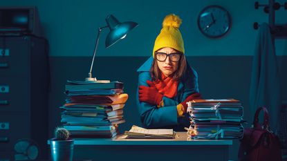 Woman huddling in a cold office