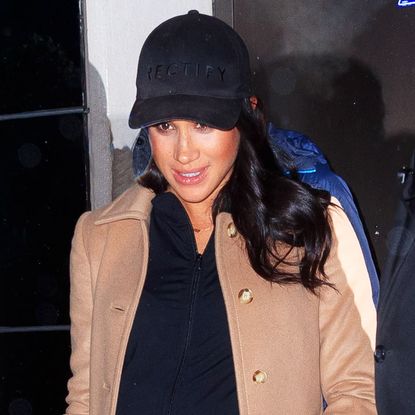 Meghan Markle wearing a tan overcoat and dark baseball cap while out in New York City in 2019.