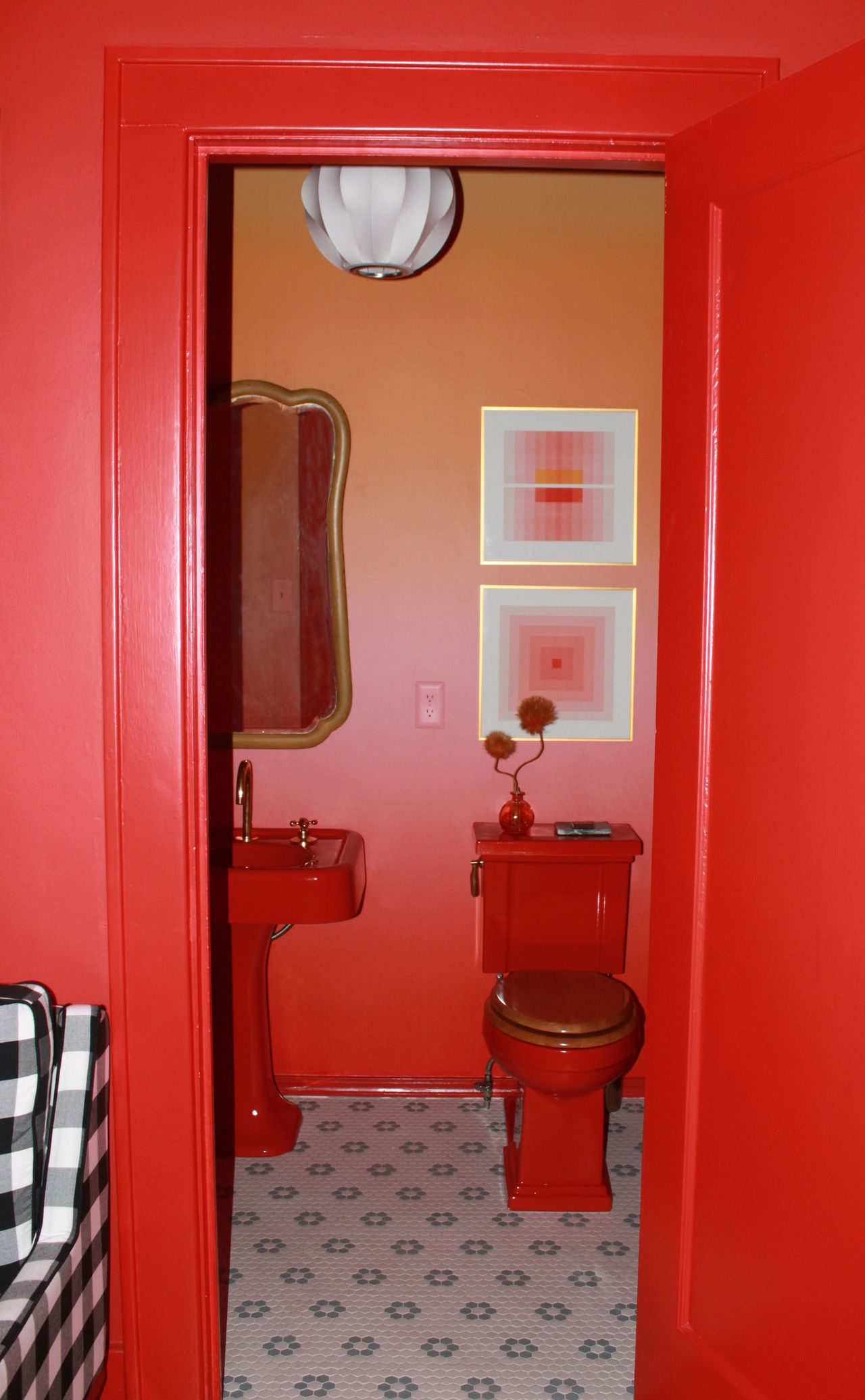 Image of a red, color-drenched bathroom. The toilet and sink are red, and the walls are a red-pink-orange ombre.