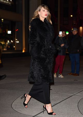 Taylor Swift wears a long black fur coat with a black dress and black heels to the Poor Things premiere in New York