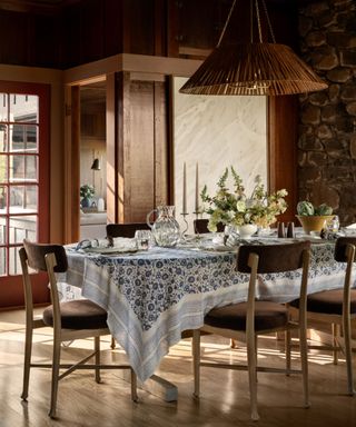 A dining room table in a wooden-walled room with a blue and white table cloth