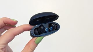 Realme Buds Air 3 earbuds in charging case held up against a wall