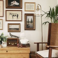 Gallery wall in gold frame with black and green images and a floor lamp